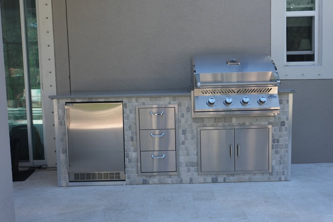 Finished custom outdoor kitchen island with built-in grill, refrigerator, storage, stonework, and counter space